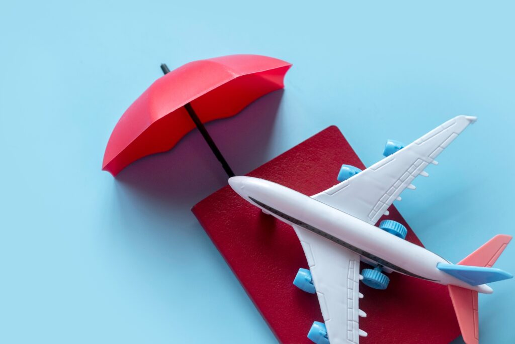 Passport, airplane model, and red umbrella representing protected travel